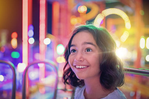 ragazza felice sorride sulla ruota panoramica in un parco divertimenti - arcade foto e immagini stock