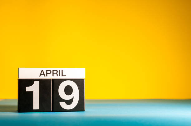 istock April 19th. Day 19 of april month, calendar on table with yellow background. Spring time, empty space for text 940306358