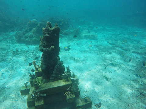 Stone statue standing on sea sandy bottom. Underwater entertainment for tourist