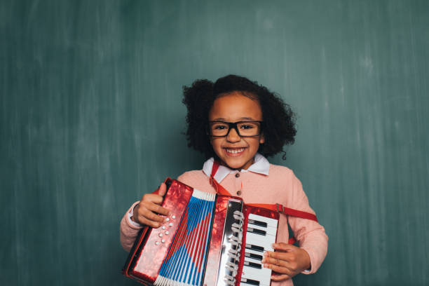 Young Retro Nerd Girl Playing Accordion A young nerd girl dressed in sweater, eyeglasses plays her accordion. She has a fun smile on her face and is ready to become a master of music. accordion instrument stock pictures, royalty-free photos & images