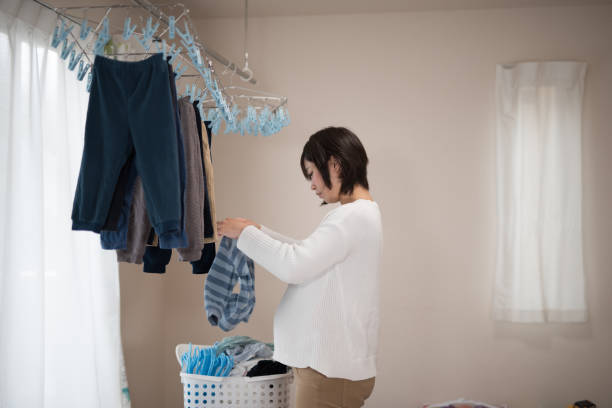istock Pregnant woman hanging laundry inside 940352684
