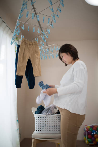 istock Pregnant woman hanging laundry inside 940355428