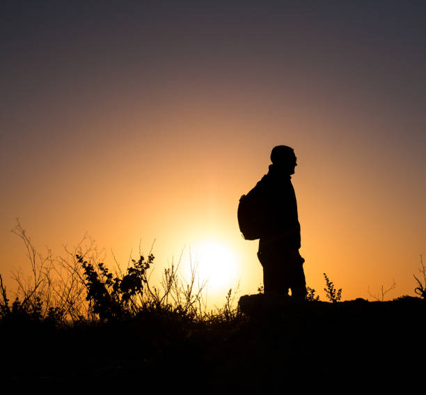 istock Silhouette of male backpacker hiking at sunset 940370236