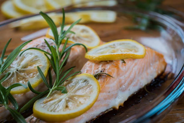 istock Salmon. Two juicy salmon steaks in roast pan with herb decoration on rustic oak table. 940374464