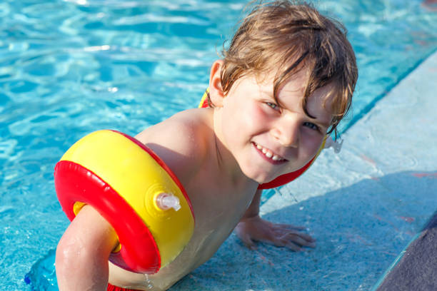 istock Happy little kid boy having fun in an swimming pool 940377652
