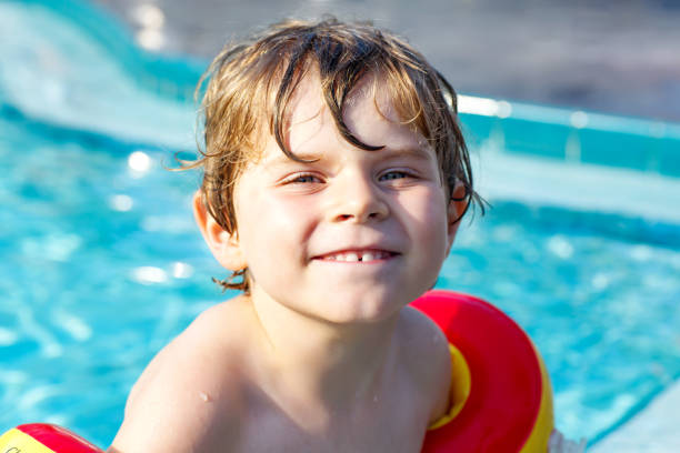 istock Happy little kid boy having fun in an swimming pool 940377824