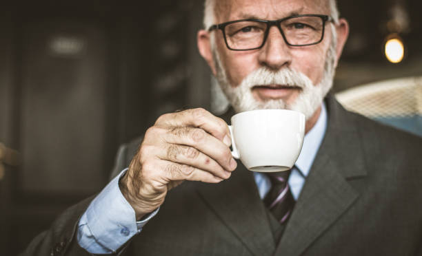 istock Senior businessman drinking coffee. Close up image. 940378698