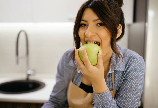 istock Young woman eating green apple 940382702