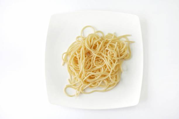 istock Spaghetti pasta on white plate, closeup, macro, top view, abstract, texture, on white background 940386352