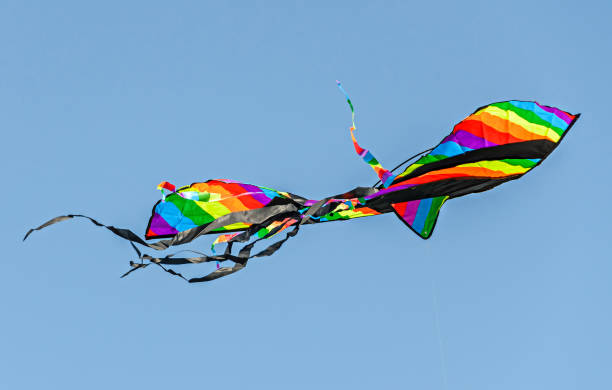 istock Colored kite flying in the blue sky, wings close up 940387528