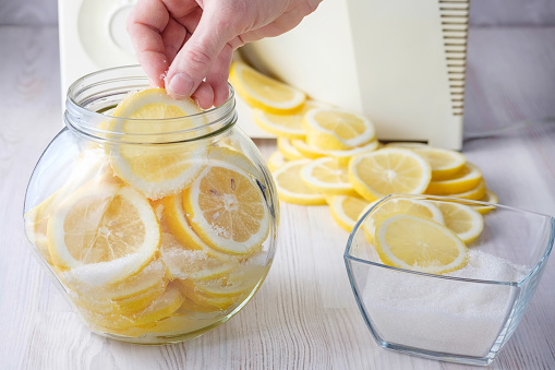 Woman's hand puts a slice of lemon in a can. Preservation of useful properties of citrus.