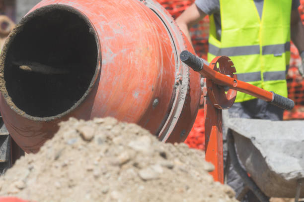 istock Construction worker on a cement / concrete mixer doing hard job. 940390746