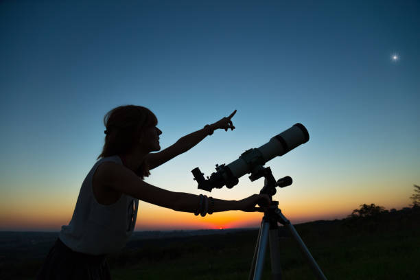 istock Young woman looking at the sky with a astronomical telescope. 940390884