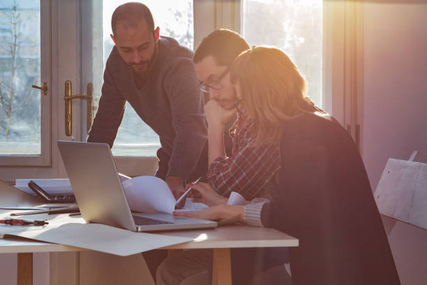 istock Group of young architects in the sunny office. 940390938