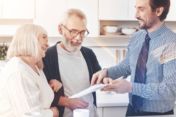 istock Cheerful delighted real estate agent talking with aged couple 940391642