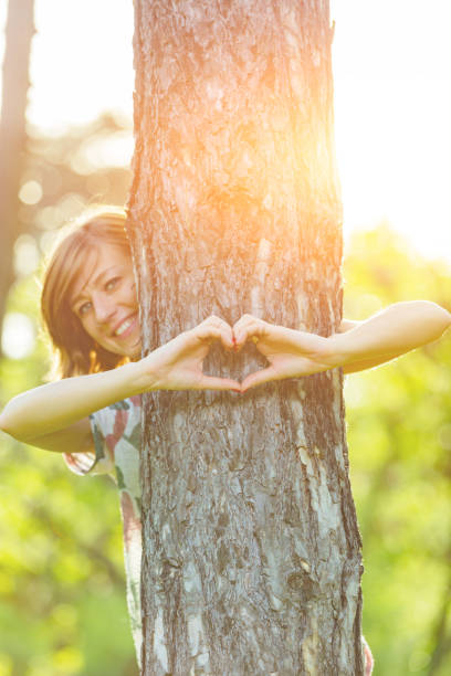 istock Girl holding a heart - shape symbol around the tree. 940391824