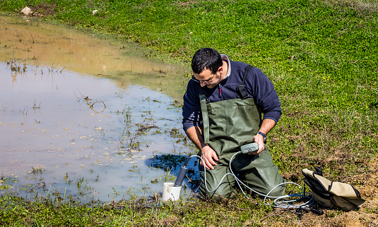 Scientist measuring environmental water quality in a wetland using a multi-parameter probe