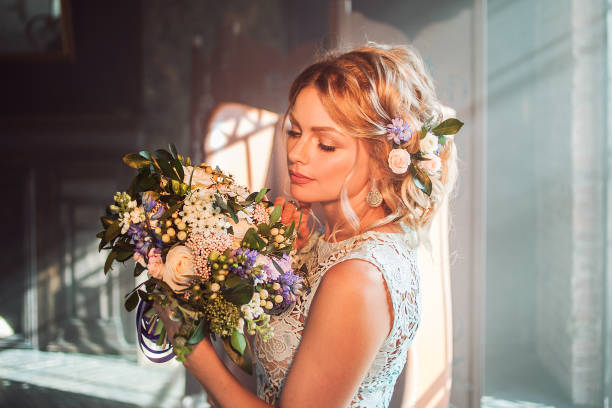 Young beautiful woman in wedding dress with bouquet of flowers. Wedding hairstyle, flowers in hair. Young beautiful woman in wedding dress with bouquet of flowers. Wedding hairstyle, flowers in hair. Bride in loft interior bridal hair stock pictures, royalty-free photos & images