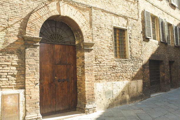 istock Old door in brick building facade in Siena 940407686