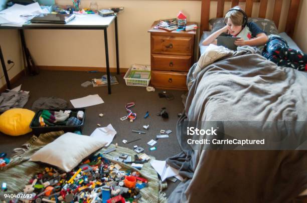 Photo libre de droit de Enfant Pose Dans Son Lit Sur Un Dispositif Électronique Avec Une Pièce Très Salissant banque d'images et plus d'images libres de droit de En désordre