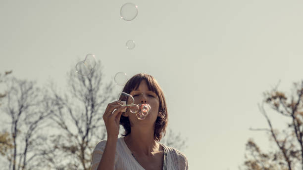 istock Front view of a woman blowing soap bubbles outside 940418340