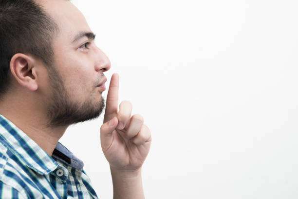 istock Young man making silence gesture isolated on white background.