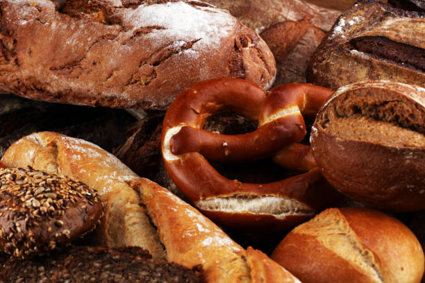 istock Different kinds of bread and bread rolls on board from above. Kitchen or bakery poster design 940426274