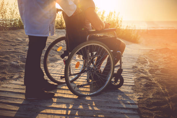 A man on wheelchair and his nurse. stock photo