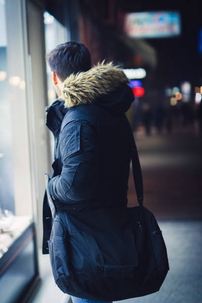 istock young man looking at store window in city at night a 940436882