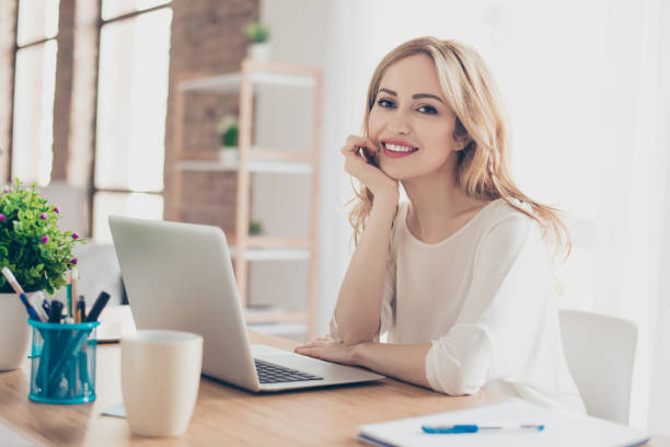 istock Happy pretty cute woman sitting at the table working with computer 940437510