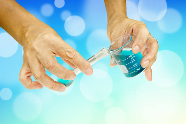 Water Purity Test. Hand holding a chemical flask or test tube with water. Lake or river in the background.