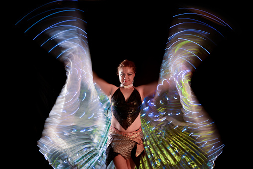 A vertical shot of a Caucasian blonde girl in angel wings costume in a park