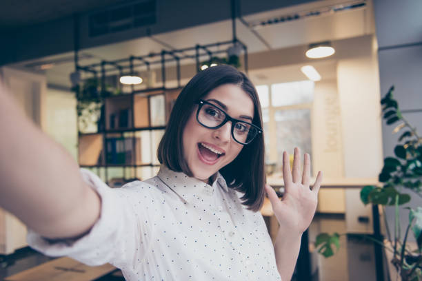 bella ragazza sorridente con gli occhiali che scatta un selfie - photography human hand portrait women foto e immagini stock