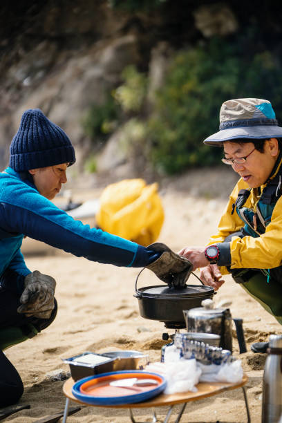 istock Two sea kayakers cooking and preparing lunch on a beach 940442106
