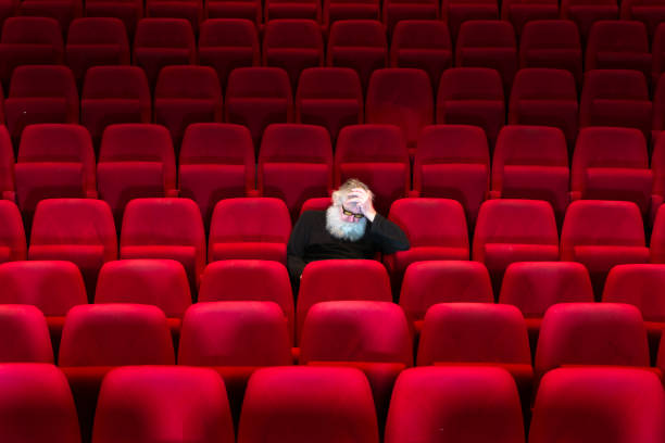 istock One man with white beard sits in Empty cinema, asleep 940442436