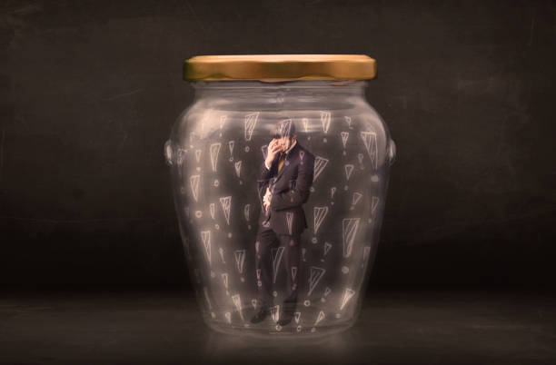 istock Business man trapped in jar with exclamation marks concept 940443216