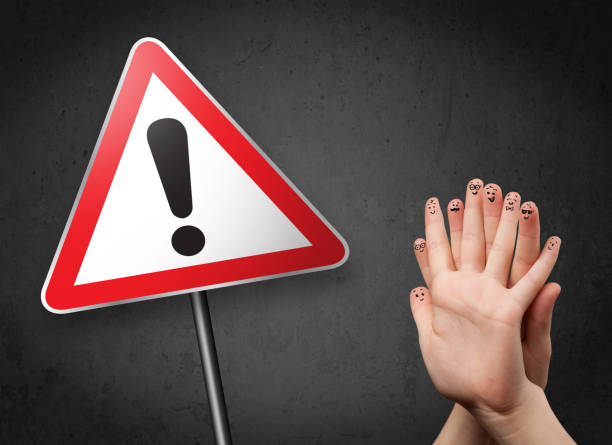 istock Happy smiley fingers looking at triangle warning sign with exclamation mark 940443424