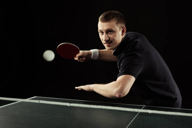 istock smiling tennis player in uniform playing table tennis isolated on black 940451076