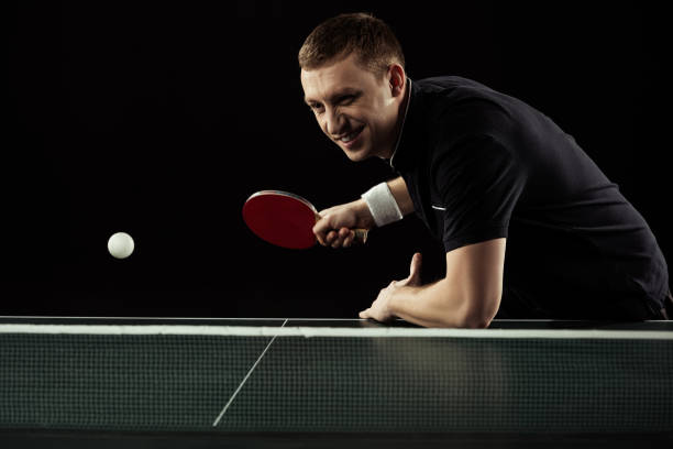 istock smiling tennis player in uniform playing table tennis isolated on black 940451334
