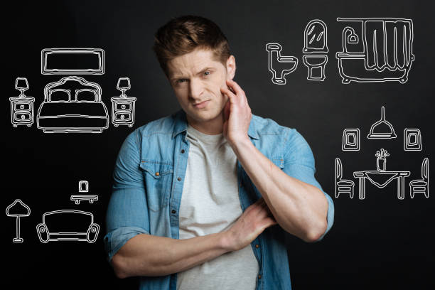 istock Young man scratching his chick while thinking about design of the room 940451346