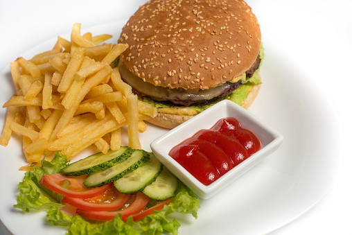 Eating fast food. Hamburger with french fries and sauce on a white plate