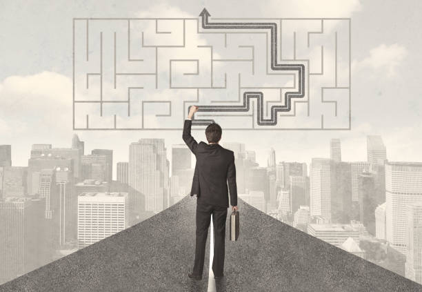 istock Businessman looking at road with maze and solution 940455840