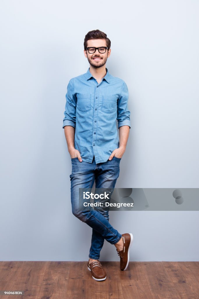 Full size vertical portrait of cheerful brunet young man in casual stylish wear. He looks at camera on lifgt background Men Stock Photo