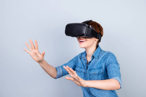 istock Happy young girl is using vh headset glasses of virtual reality, touching something with her hands like a touch screen 940463340
