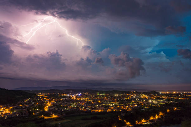 Multi-colored lightning storm over bright city at night stock photo