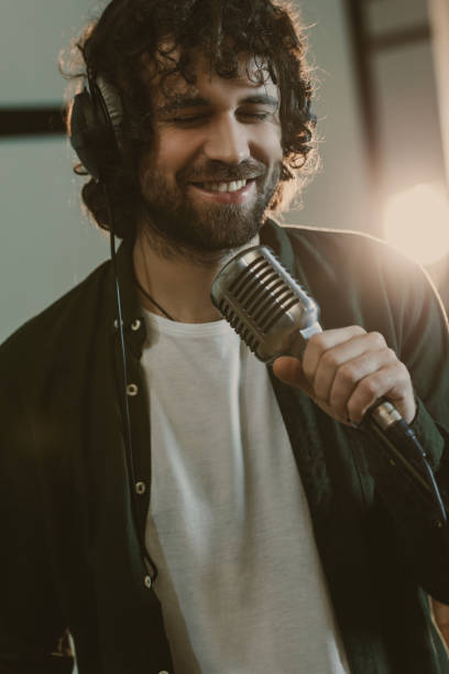 istock handsome young singer in headphone performing song at studio 940469646