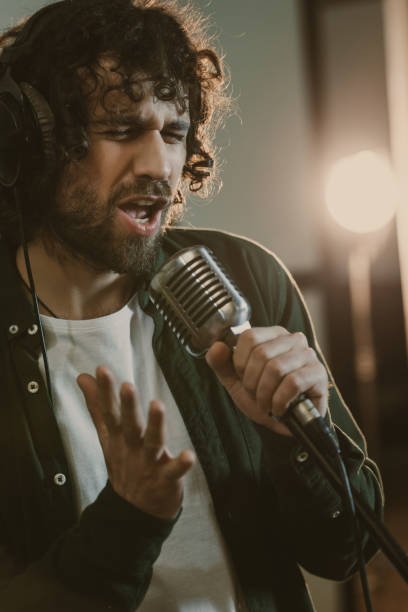 istock emotional young singer in headphone performing song at studio 940472214