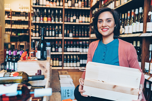 Smiling young woman working in a wine shop