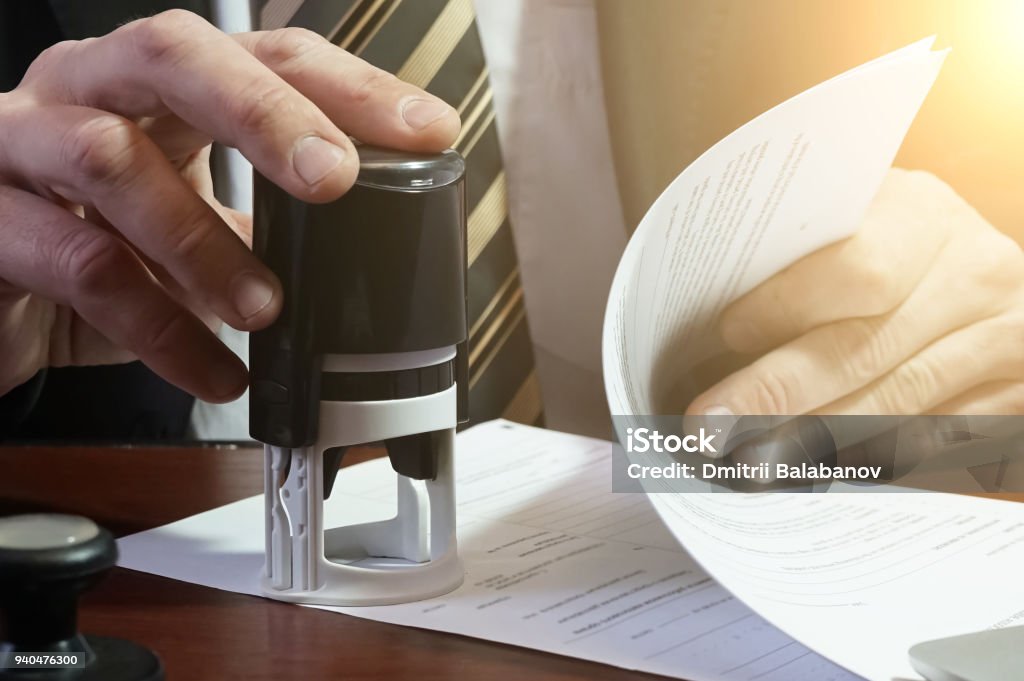 The businessman puts a stamp on the contract The businessman puts a stamp on the contract. Copy space. Intellectual Property Stock Photo