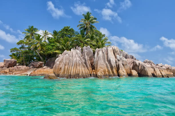 The iconic golden sands, gently lapping Indian Ocean surf, sculpted rocks and swaying palms of the Anse Source d'Argent beach under tropical skies on the picturesque island of La Digue, Seychelles. ProPhoto RGB profile for maximum color fidelity and gamut.